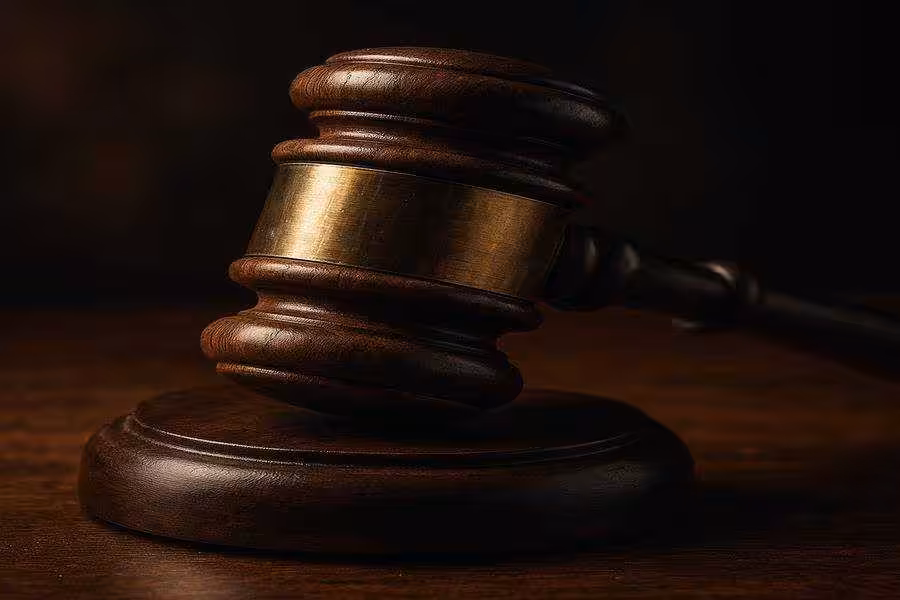 A hyper-realistic close-up photograph of a judge’s wooden gavel resting on a matching sound block, showcasing the rich wood grain and brass band under dramatic lighting.
